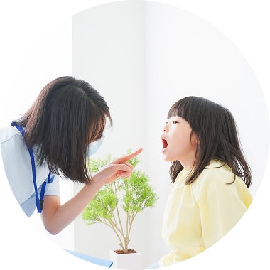 歯科助手の方に女の子が口を開けてみてもらっている写真