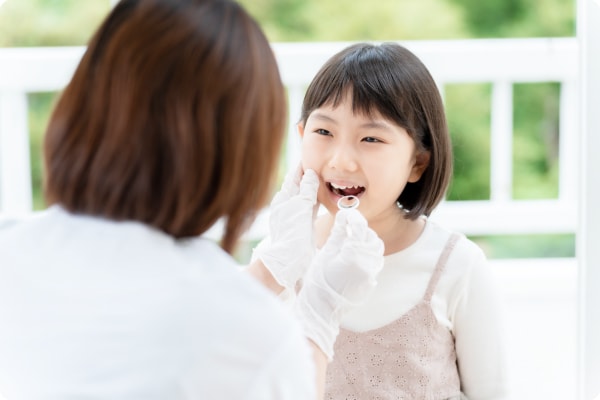 歯科医院で女性に口の中を診てもらう子どもの写真